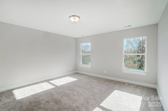 spare room featuring light carpet, visible vents, and baseboards