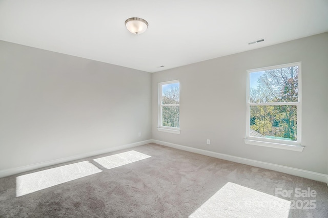 spare room with baseboards, visible vents, and light colored carpet