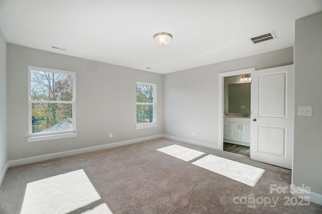 unfurnished bedroom featuring a sink, carpet flooring, visible vents, and baseboards