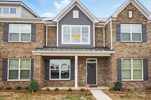 view of front of house featuring a standing seam roof, brick siding, and metal roof