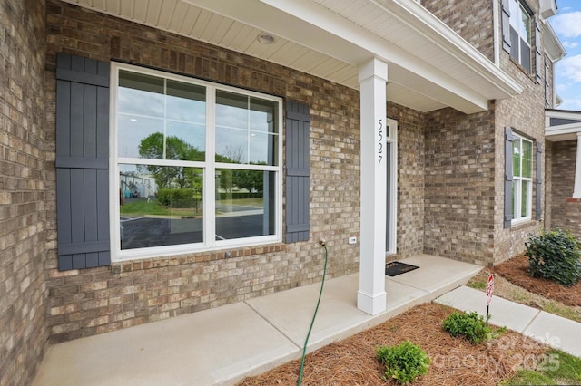 entrance to property with brick siding and a porch