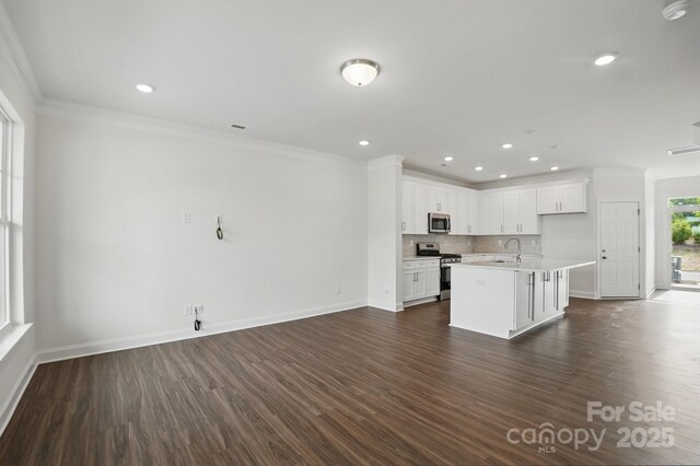 kitchen with stainless steel appliances, a sink, tasteful backsplash, open floor plan, and baseboards
