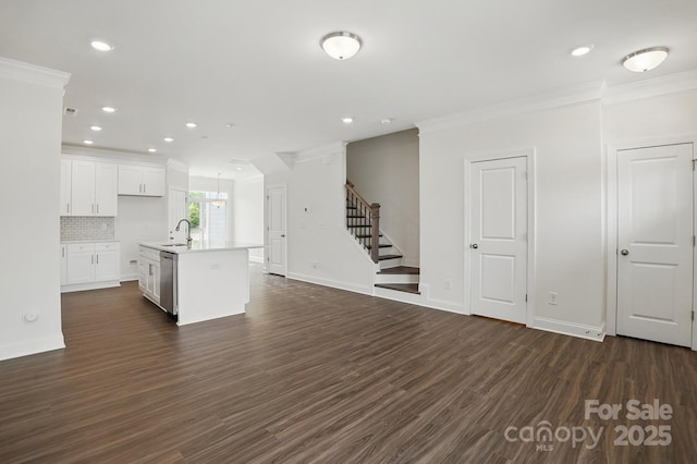 kitchen featuring a sink, an island with sink, white cabinetry, dark wood finished floors, and ornamental molding