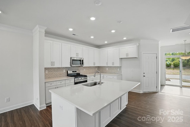 kitchen featuring dark wood-style floors, stainless steel appliances, a sink, baseboards, and decorative backsplash