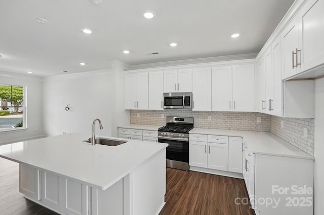 kitchen with white cabinets, a sink, appliances with stainless steel finishes, and dark wood-style flooring