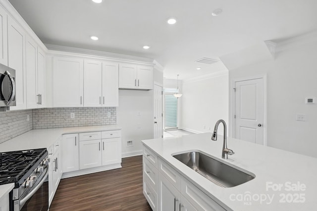 kitchen with white cabinets, appliances with stainless steel finishes, ornamental molding, and a sink