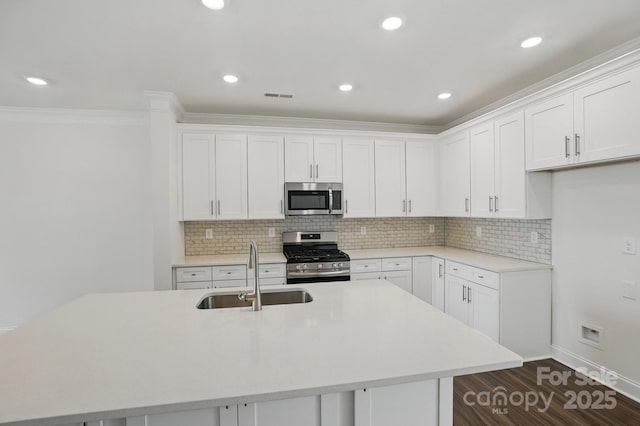 kitchen with stainless steel appliances, light countertops, visible vents, a sink, and decorative backsplash