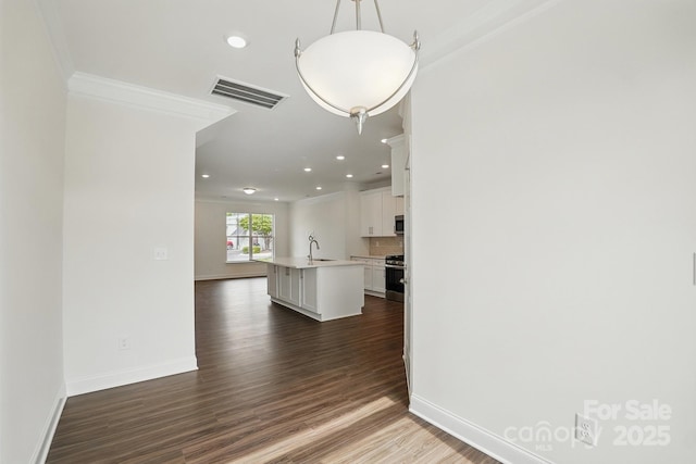 interior space with an island with sink, visible vents, ornamental molding, a sink, and appliances with stainless steel finishes