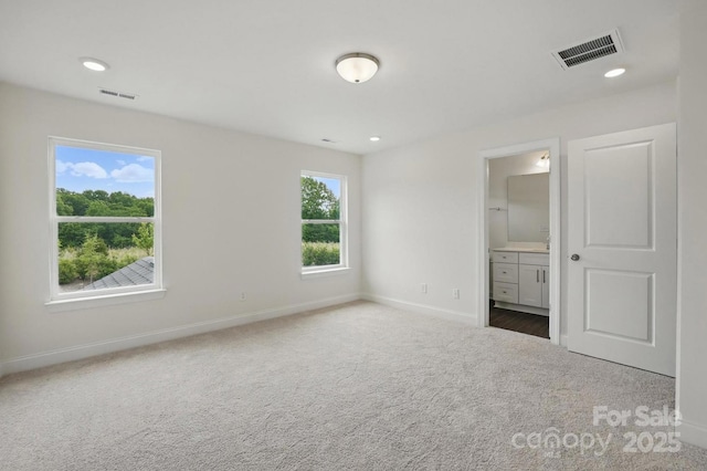 unfurnished bedroom with carpet floors, visible vents, baseboards, and connected bathroom