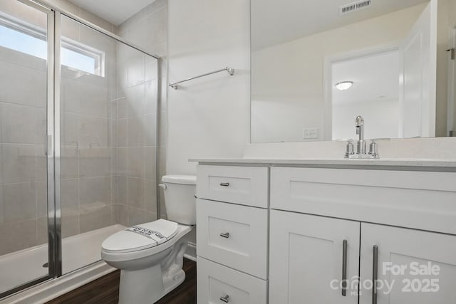 bathroom with visible vents, toilet, a stall shower, and vanity