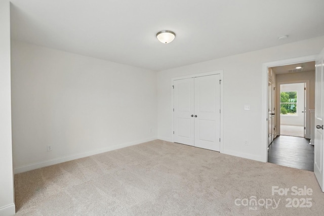 unfurnished bedroom with baseboards, carpet floors, and a closet
