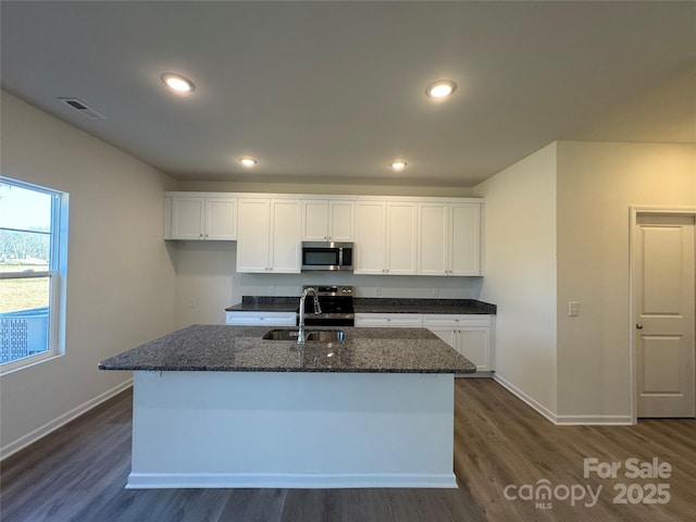 kitchen with white cabinets, appliances with stainless steel finishes, a center island with sink, and sink