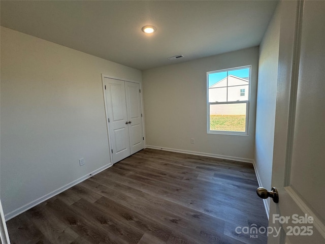 unfurnished bedroom featuring a closet and dark hardwood / wood-style floors