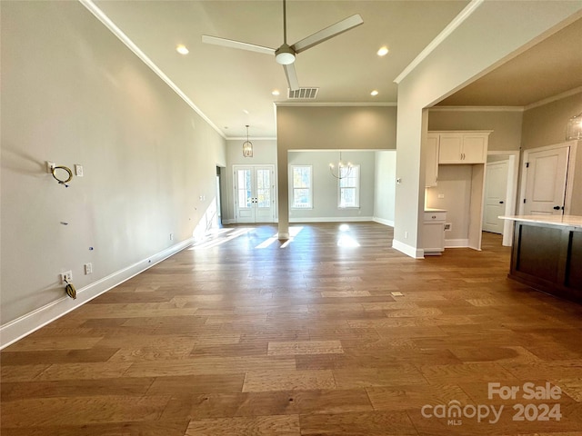 unfurnished living room featuring hardwood / wood-style floors, ceiling fan with notable chandelier, and ornamental molding