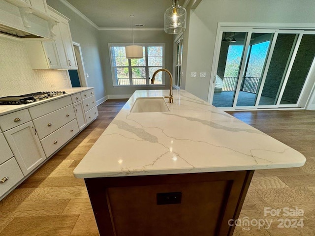 kitchen featuring a kitchen island with sink, crown molding, sink, hanging light fixtures, and extractor fan