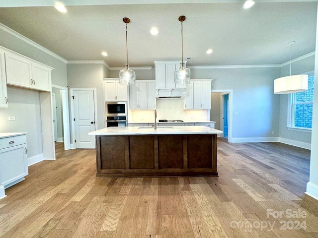 kitchen featuring appliances with stainless steel finishes, light wood-type flooring, decorative light fixtures, and white cabinetry