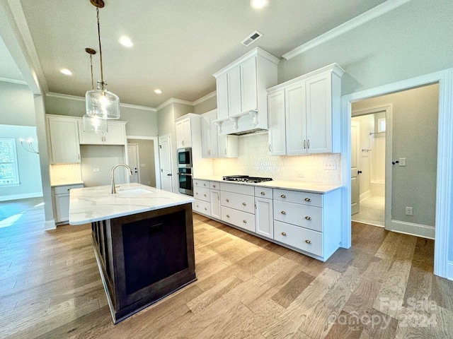 kitchen with white cabinetry, sink, decorative light fixtures, a kitchen island with sink, and appliances with stainless steel finishes