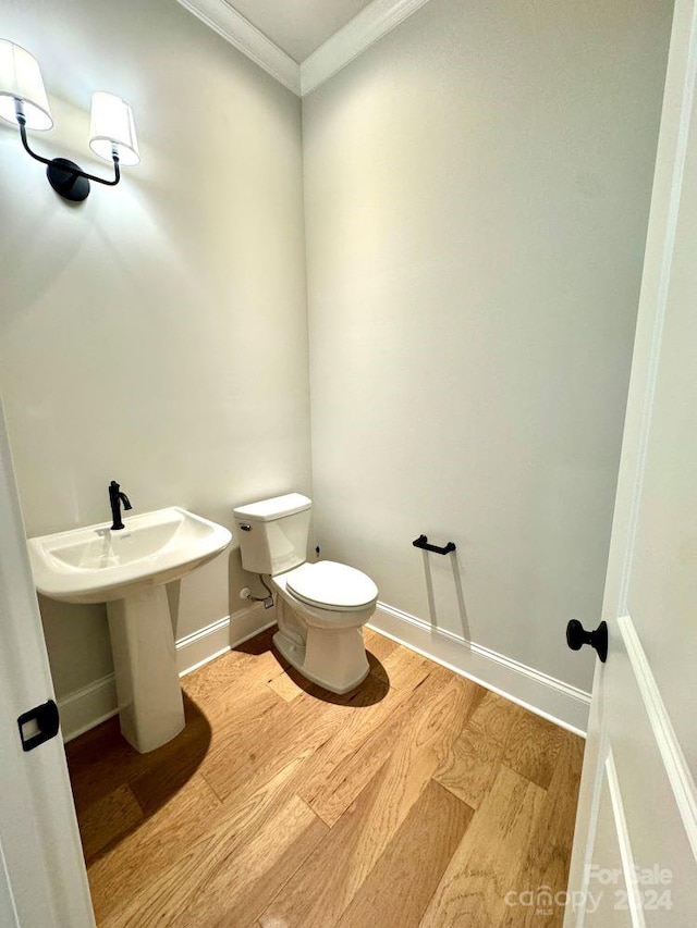 bathroom featuring wood-type flooring, toilet, and ornamental molding