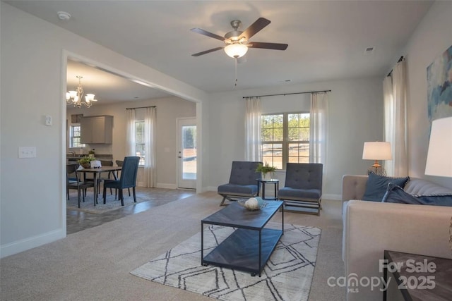 living room with ceiling fan with notable chandelier and light colored carpet