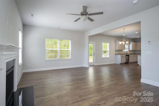 unfurnished living room featuring ceiling fan with notable chandelier and dark hardwood / wood-style flooring