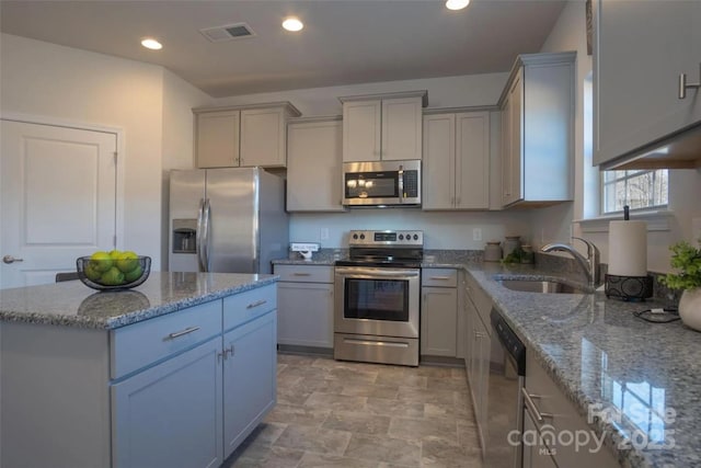 kitchen featuring light stone countertops, sink, gray cabinetry, and stainless steel appliances