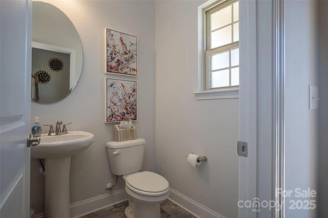 bathroom with toilet, plenty of natural light, and sink