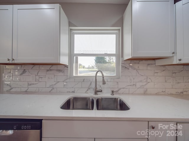 kitchen featuring white cabinetry, sink, tasteful backsplash, light stone counters, and stainless steel dishwasher