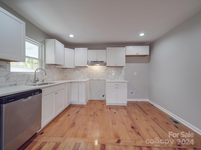 kitchen with stainless steel dishwasher, white cabinets, sink, and light hardwood / wood-style flooring