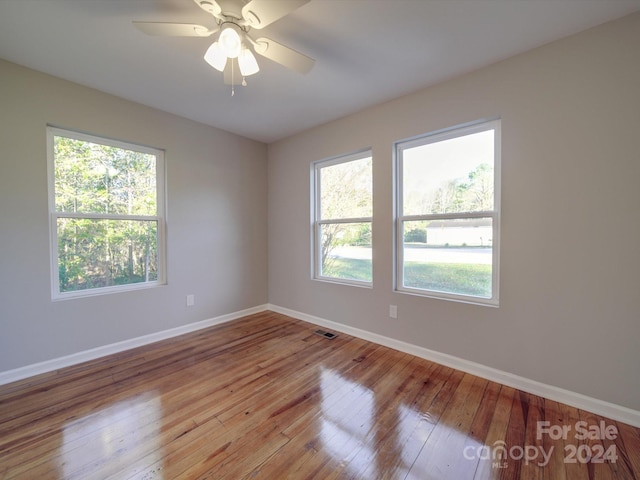 spare room with ceiling fan, a healthy amount of sunlight, and light hardwood / wood-style floors