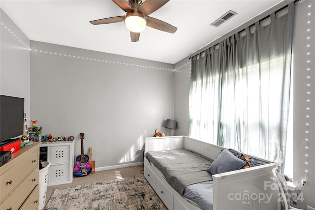 bedroom with multiple windows, ceiling fan, and light colored carpet