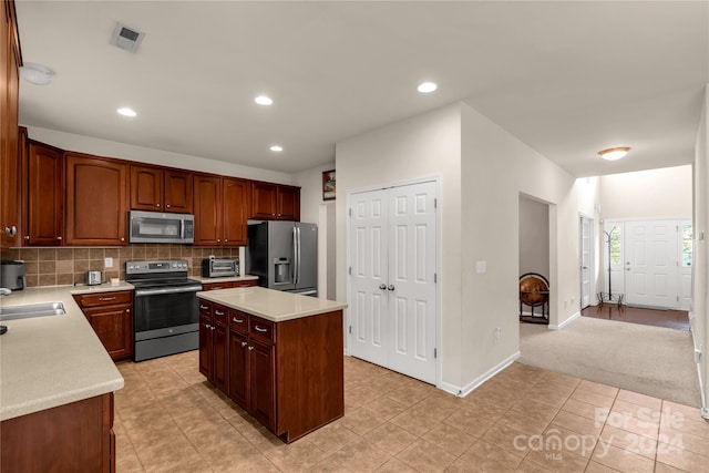 kitchen with backsplash, a kitchen island, light tile patterned floors, and appliances with stainless steel finishes