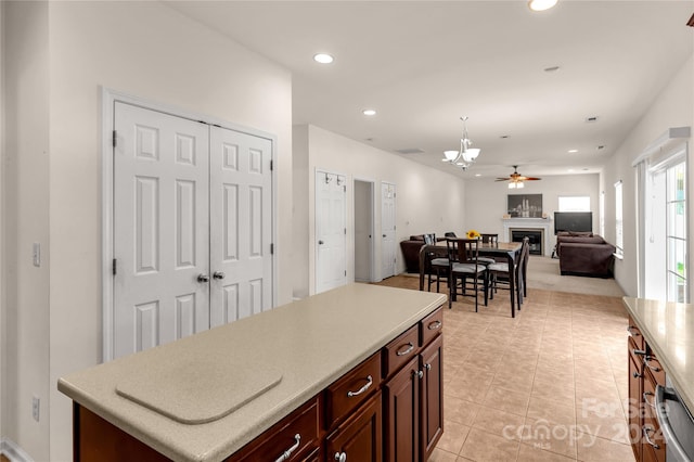 kitchen with dishwasher, a kitchen island, light tile patterned flooring, and ceiling fan with notable chandelier