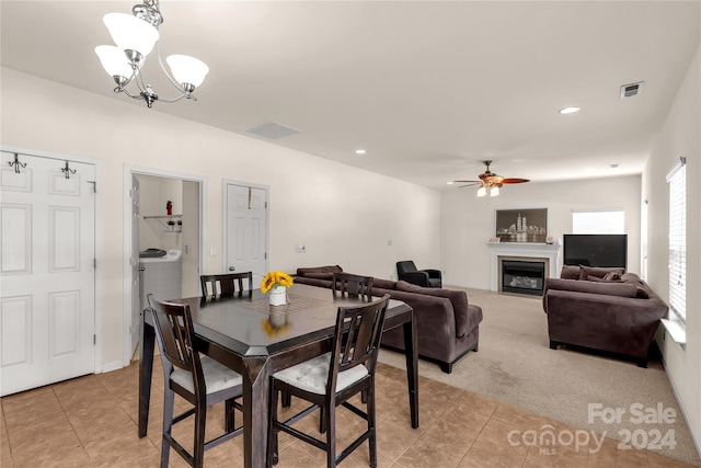 carpeted dining space featuring ceiling fan with notable chandelier