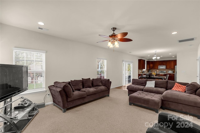 living room with ceiling fan with notable chandelier and carpet floors