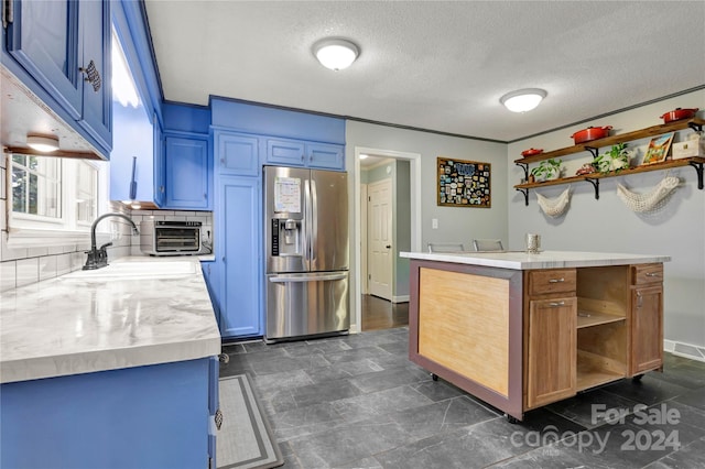 kitchen with stainless steel refrigerator with ice dispenser, backsplash, a textured ceiling, and blue cabinets