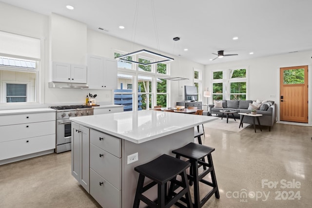 kitchen featuring white cabinets, ceiling fan, high end stove, a kitchen island, and a breakfast bar area