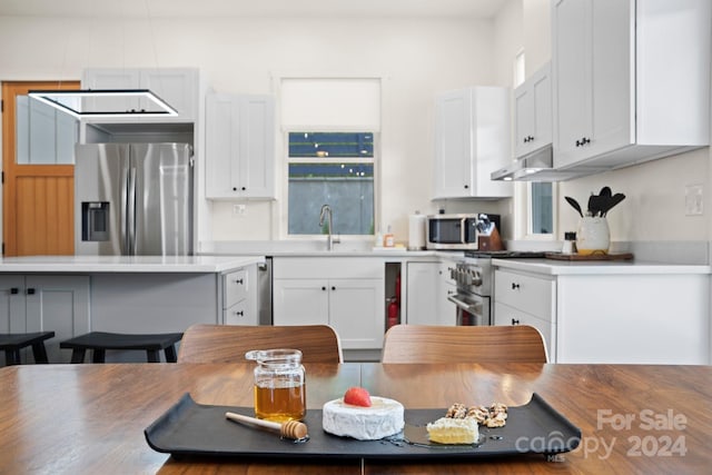 kitchen featuring white cabinets, a breakfast bar, stainless steel appliances, and sink