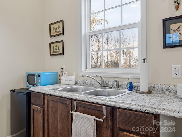 kitchen featuring stainless steel fridge, dark brown cabinetry, and sink