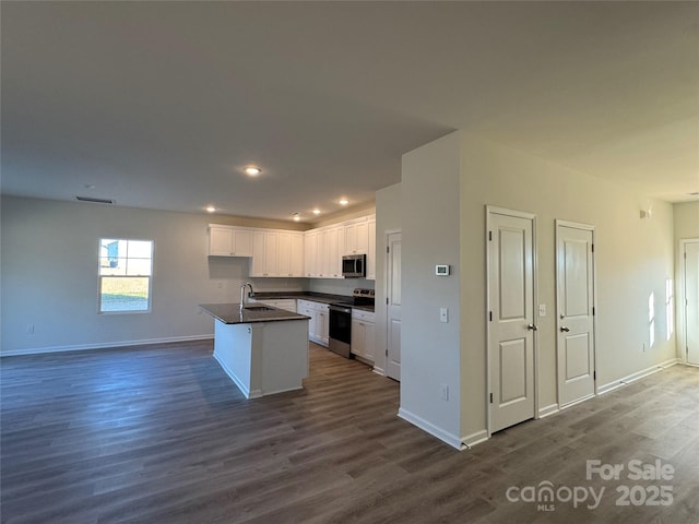 kitchen with white cabinetry, sink, dark wood-type flooring, an island with sink, and appliances with stainless steel finishes