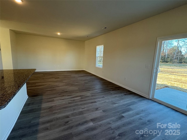 unfurnished living room featuring dark hardwood / wood-style flooring and a wealth of natural light