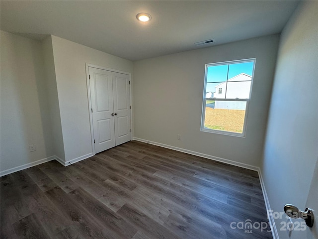 unfurnished bedroom featuring dark wood-type flooring and a closet