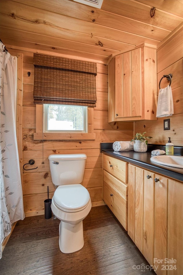 bathroom featuring hardwood / wood-style flooring, vanity, toilet, and wooden walls