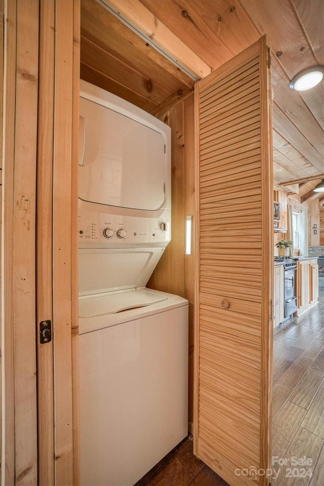 laundry area with dark wood-type flooring, stacked washer and dryer, wooden walls, and wood ceiling