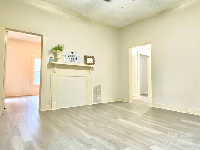 unfurnished living room featuring hardwood / wood-style flooring, ornamental molding, and a textured ceiling