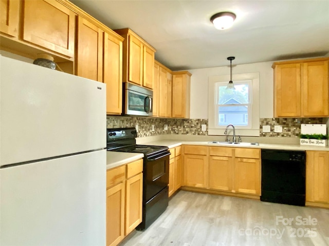 kitchen featuring light countertops, decorative backsplash, a sink, light wood-type flooring, and black appliances