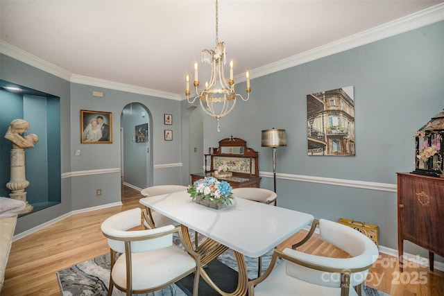 dining area with light wood-type flooring, an inviting chandelier, and crown molding