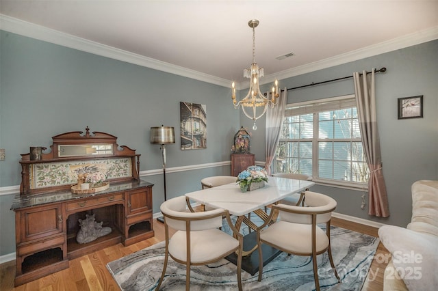 dining area featuring a chandelier, light hardwood / wood-style flooring, and ornamental molding