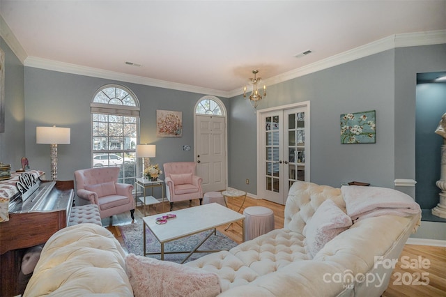 living room with french doors, light wood-type flooring, crown molding, and a notable chandelier