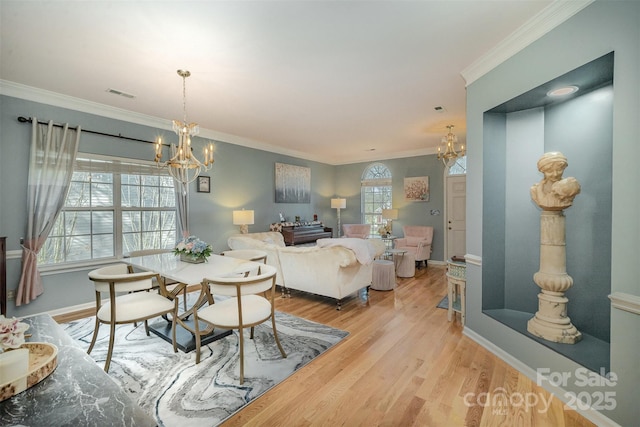 dining area with light hardwood / wood-style floors, an inviting chandelier, and ornamental molding