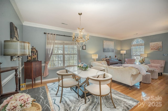 dining space with crown molding, light hardwood / wood-style floors, and a notable chandelier